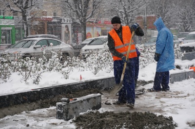 У Чернівцях робітники у снігопад встановлюють бордюри на проспекті - фото